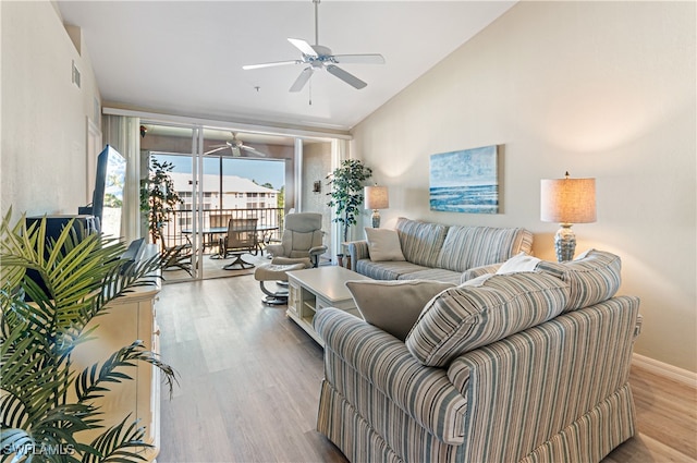 living room with ceiling fan, light hardwood / wood-style floors, and vaulted ceiling