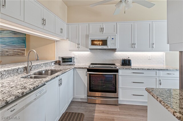 kitchen with white appliances, white cabinetry, and sink