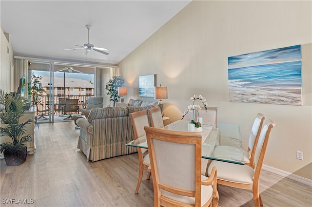 dining space with lofted ceiling, ceiling fan, light wood-type flooring, and expansive windows