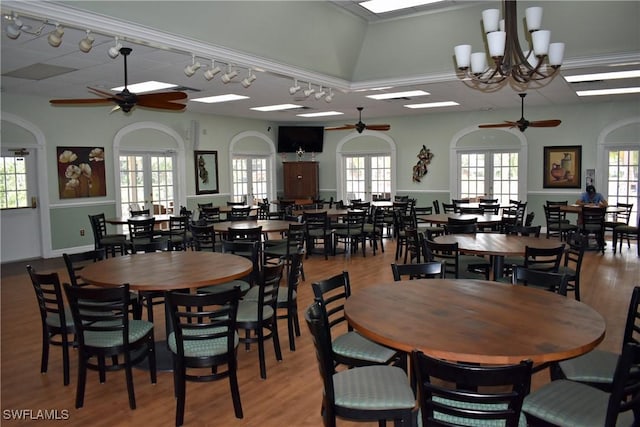 dining room with ceiling fan with notable chandelier, vaulted ceiling, light wood-type flooring, and french doors