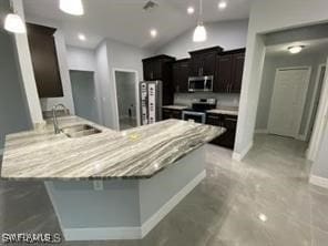 kitchen featuring sink, vaulted ceiling, light stone countertops, and appliances with stainless steel finishes