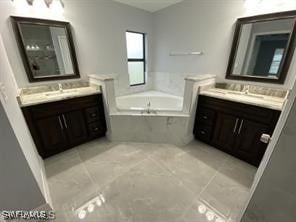 bathroom with tiled tub, vanity, and tile patterned flooring