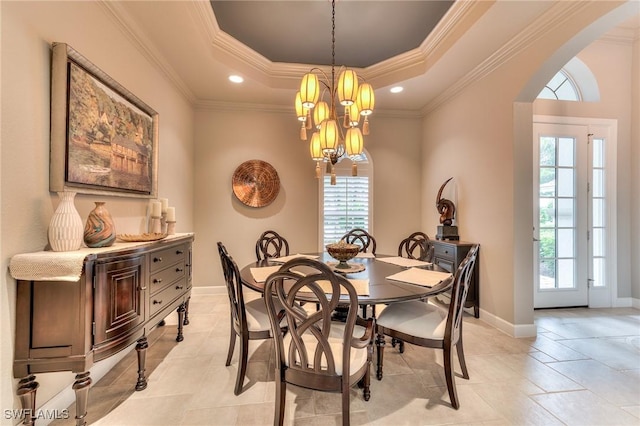 dining area with a raised ceiling, ornamental molding, and a notable chandelier