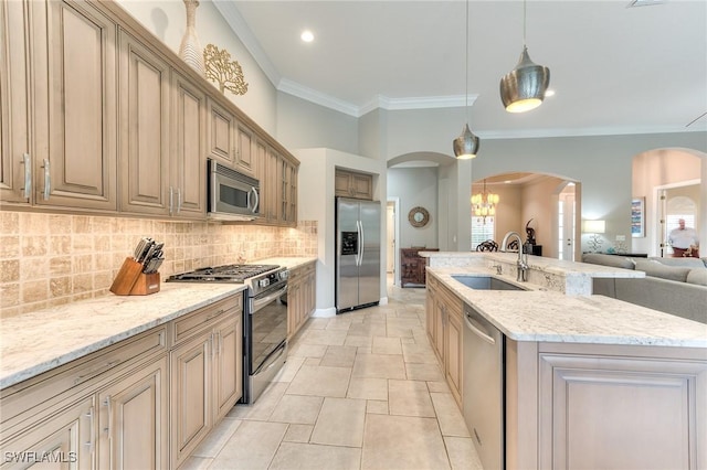 kitchen with sink, decorative light fixtures, backsplash, a center island with sink, and appliances with stainless steel finishes