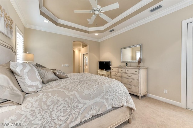 carpeted bedroom with ceiling fan, a tray ceiling, and ornamental molding