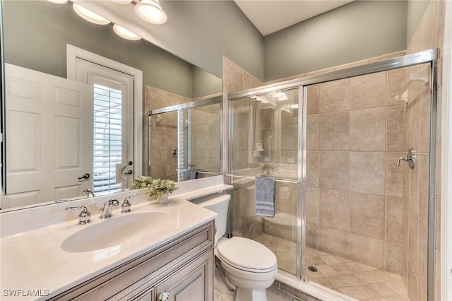 bathroom featuring toilet, vanity, and a shower with shower door