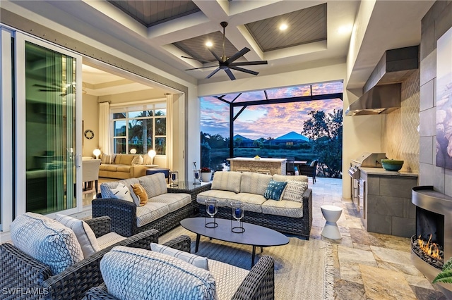 patio terrace at dusk with ceiling fan, an outdoor hangout area, exterior kitchen, and a grill