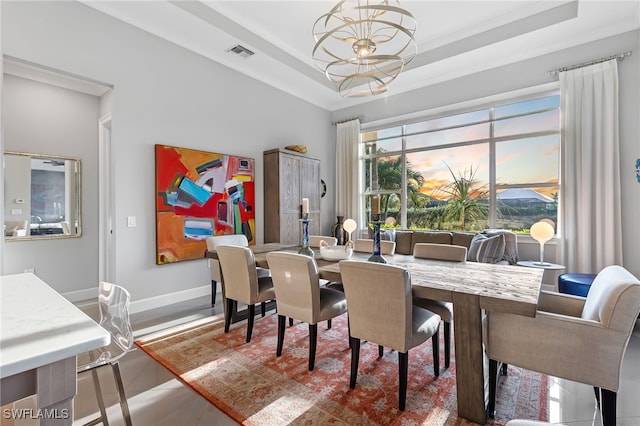 dining room featuring a raised ceiling, tile patterned flooring, and a chandelier