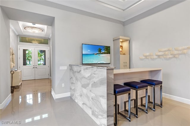 bar with a tray ceiling, light tile patterned floors, crown molding, and french doors