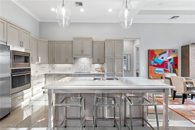 kitchen with decorative backsplash, sink, a kitchen island with sink, a kitchen breakfast bar, and stainless steel appliances