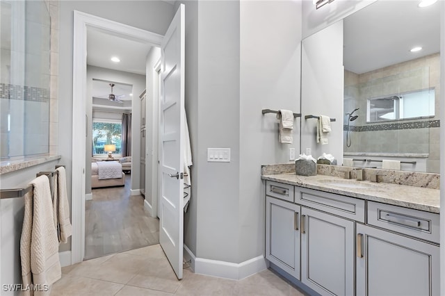 bathroom with tile patterned flooring, tiled shower, and vanity