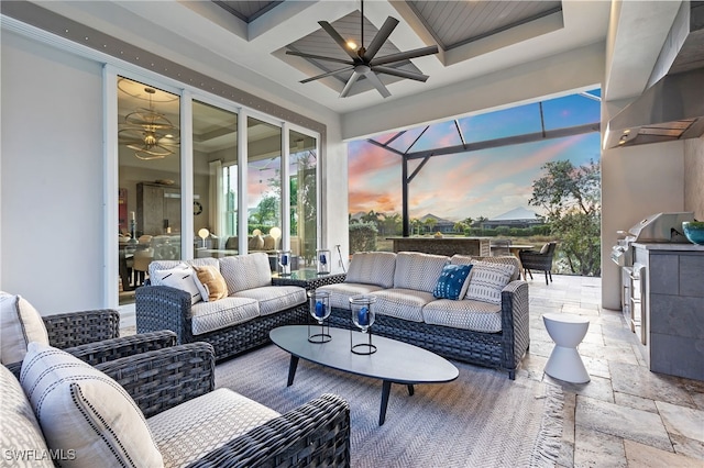 patio terrace at dusk featuring ceiling fan, glass enclosure, an outdoor kitchen, and an outdoor hangout area