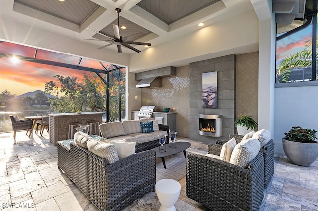 patio terrace at dusk with exterior bar, area for grilling, and an outdoor living space with a fireplace