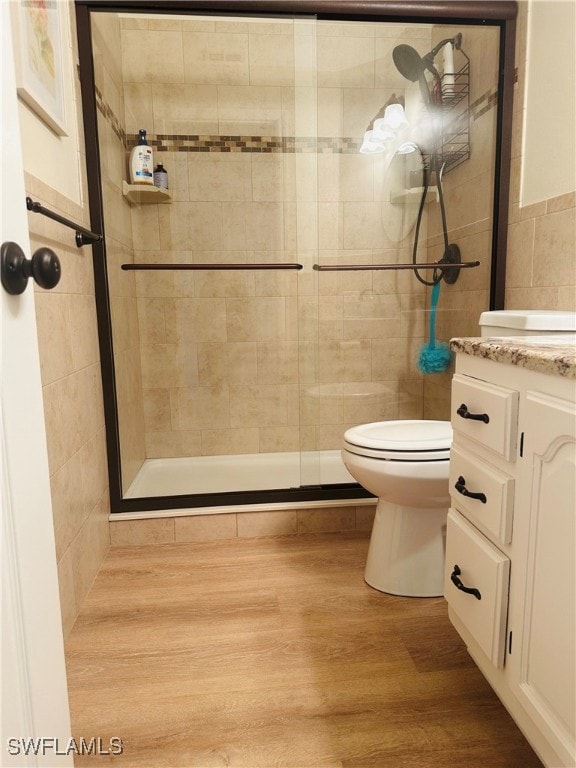 bathroom featuring a shower with shower door, wood-type flooring, toilet, and vanity