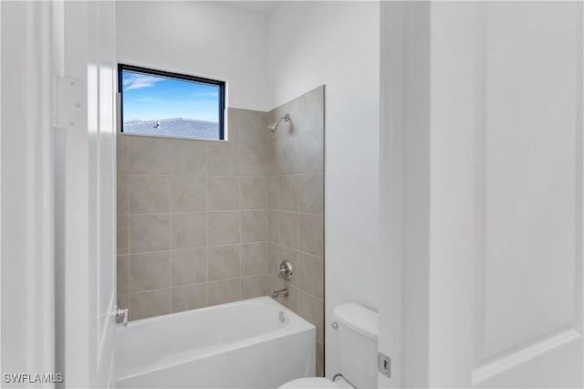 bathroom with toilet and tiled shower / bath