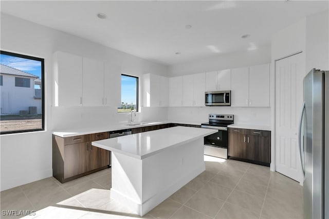 kitchen featuring dark brown cabinetry, white cabinetry, a center island, sink, and appliances with stainless steel finishes