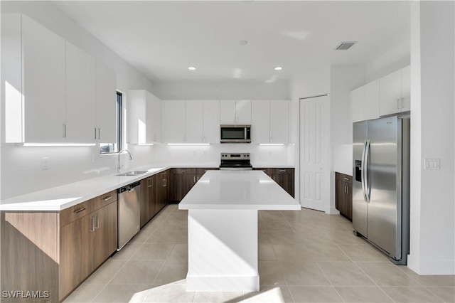 kitchen with white cabinets, sink, a kitchen island, and appliances with stainless steel finishes