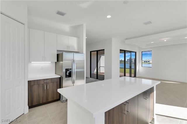 kitchen with a kitchen island, white cabinetry, stainless steel refrigerator with ice dispenser, and light tile patterned floors