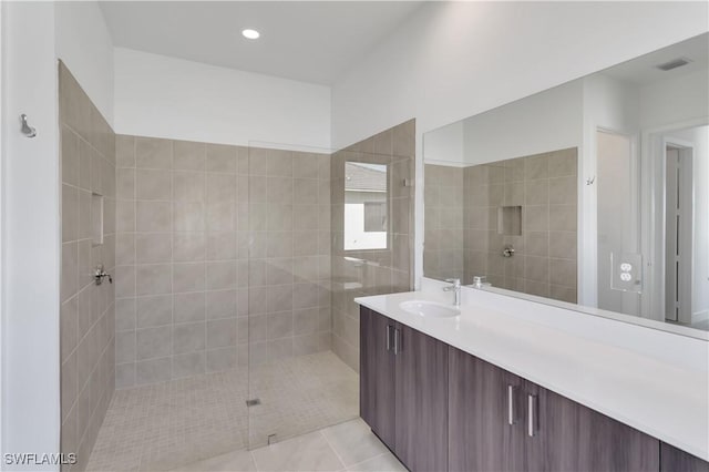 bathroom with tile patterned flooring, vanity, and tiled shower