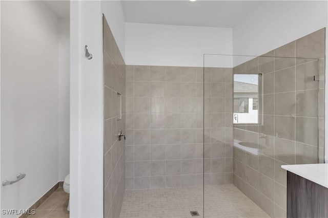 bathroom with tile patterned flooring, vanity, tiled shower, and toilet