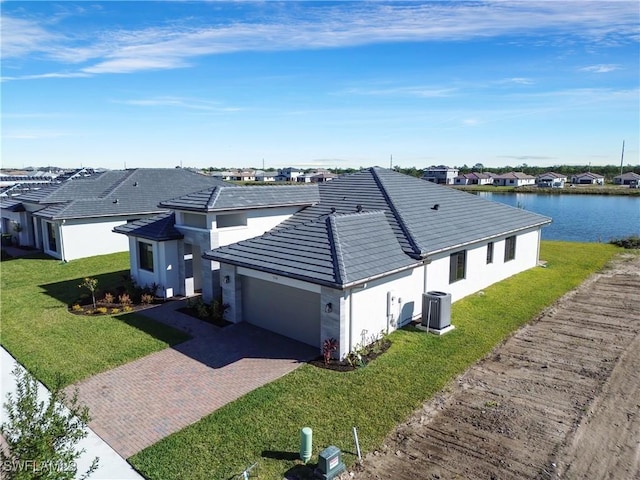 exterior space featuring a garage, a water view, a front yard, and central AC