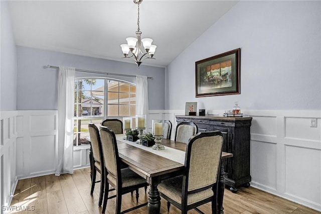 dining space with lofted ceiling, a chandelier, and light hardwood / wood-style flooring