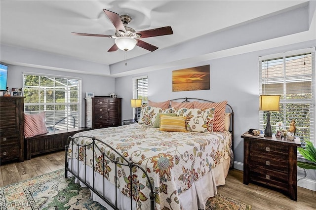 bedroom featuring ceiling fan, multiple windows, and light hardwood / wood-style flooring