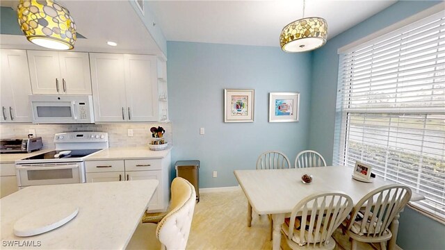 kitchen featuring decorative light fixtures, white cabinets, backsplash, and white appliances