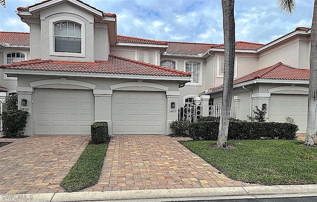 mediterranean / spanish-style house featuring decorative driveway, a tile roof, and stucco siding