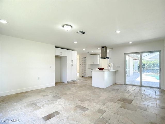 kitchen with kitchen peninsula, island exhaust hood, and white cabinetry