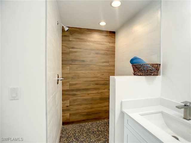 bathroom with walk in shower, vanity, and wood walls