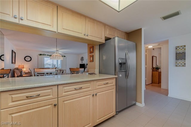 kitchen featuring pendant lighting, stainless steel fridge with ice dispenser, light brown cabinetry, and kitchen peninsula