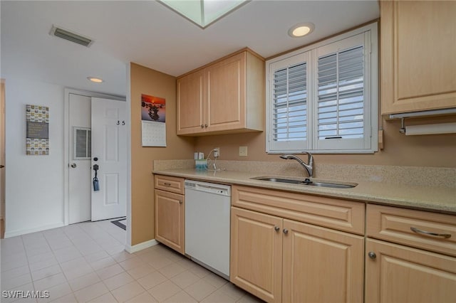 kitchen with white dishwasher, sink, light tile patterned floors, and light brown cabinets