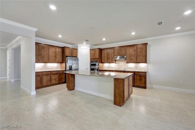 kitchen with decorative backsplash, light stone countertops, a kitchen island with sink, crown molding, and appliances with stainless steel finishes