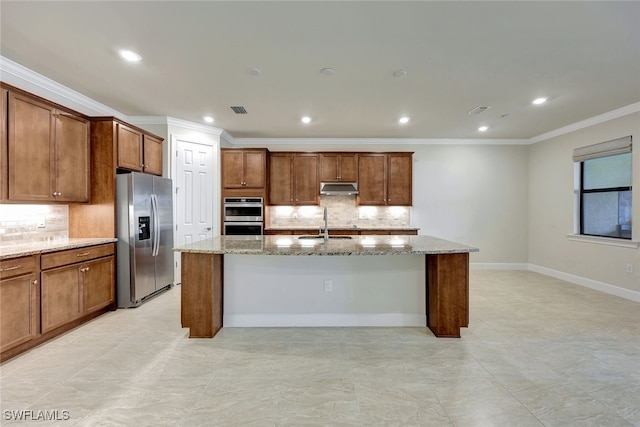 kitchen with stainless steel appliances, ornamental molding, backsplash, light stone countertops, and a center island with sink