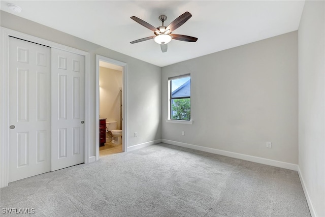 unfurnished bedroom featuring ensuite bath, light colored carpet, ceiling fan, and a closet