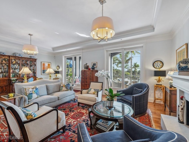 living room featuring light hardwood / wood-style floors, a raised ceiling, and ornamental molding