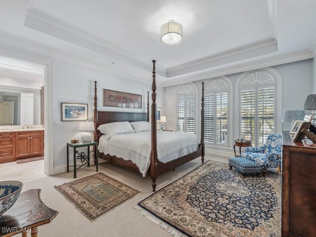 carpeted bedroom featuring a raised ceiling, ensuite bathroom, sink, and ornamental molding