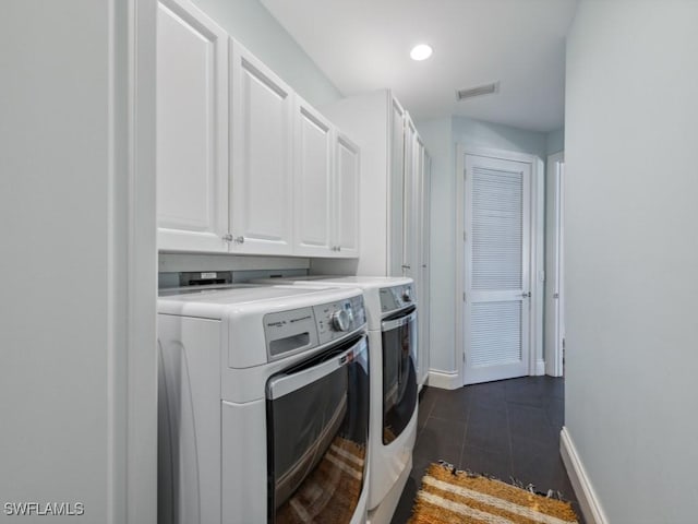 clothes washing area featuring dark tile patterned floors, cabinets, and independent washer and dryer