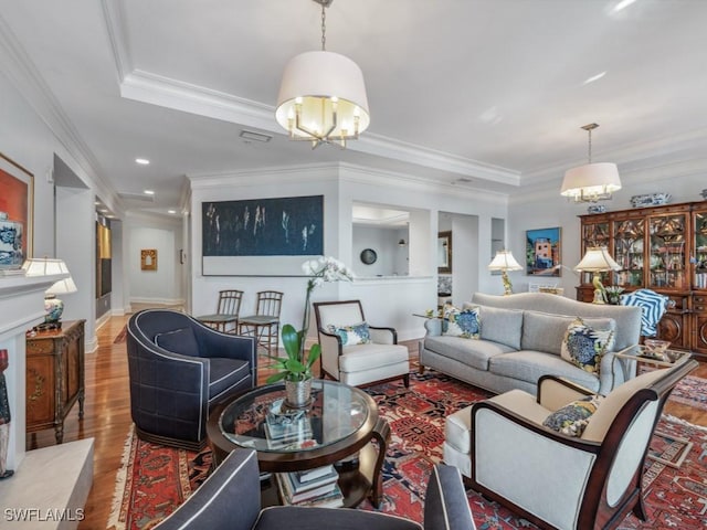 living room with hardwood / wood-style flooring, a notable chandelier, and crown molding