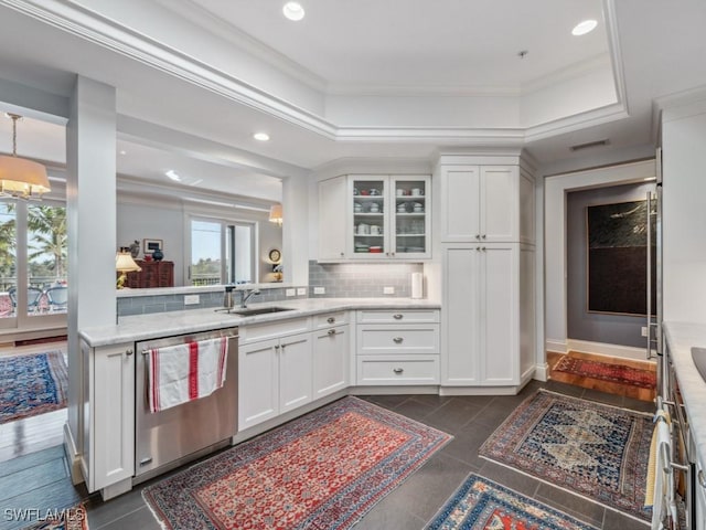 kitchen with stainless steel dishwasher, a raised ceiling, white cabinetry, and tasteful backsplash