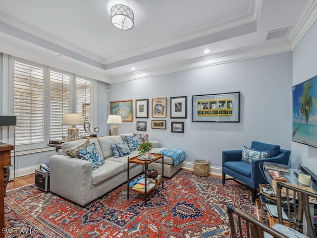 living room with hardwood / wood-style floors, a raised ceiling, and crown molding