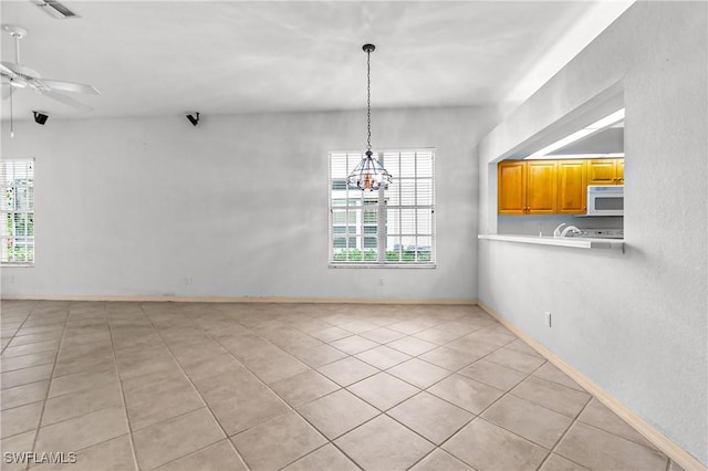 unfurnished dining area with ceiling fan with notable chandelier and light tile patterned floors