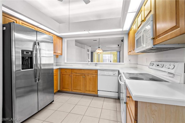 kitchen with hanging light fixtures, sink, light tile patterned flooring, and white appliances