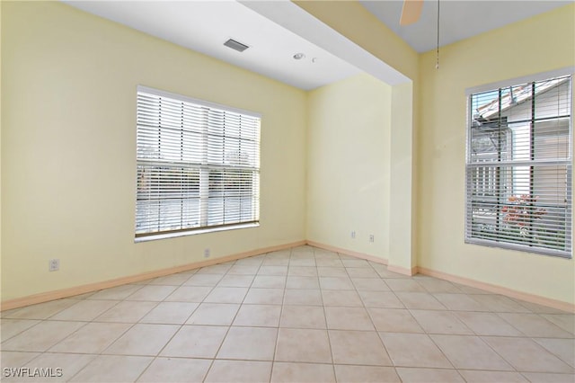 tiled empty room featuring ceiling fan and a wealth of natural light