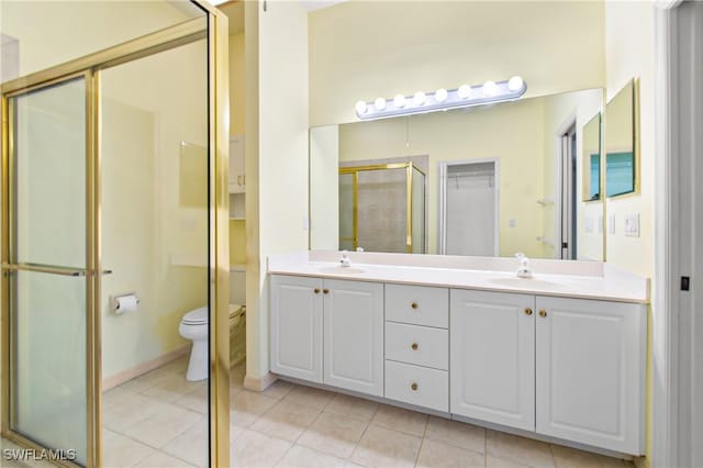 bathroom with toilet, tile patterned flooring, a shower with shower door, and vanity