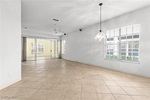 tiled spare room featuring ceiling fan with notable chandelier