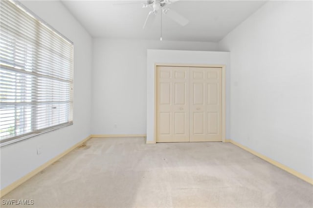 unfurnished bedroom with light carpet, ceiling fan, and a closet