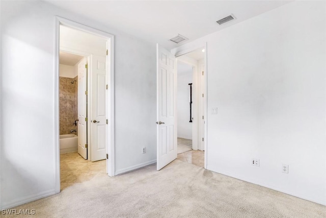 unfurnished bedroom with light colored carpet and connected bathroom