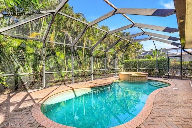 view of swimming pool featuring glass enclosure, a patio area, and an in ground hot tub